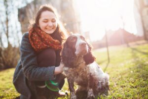 A lady leaning down by her dog