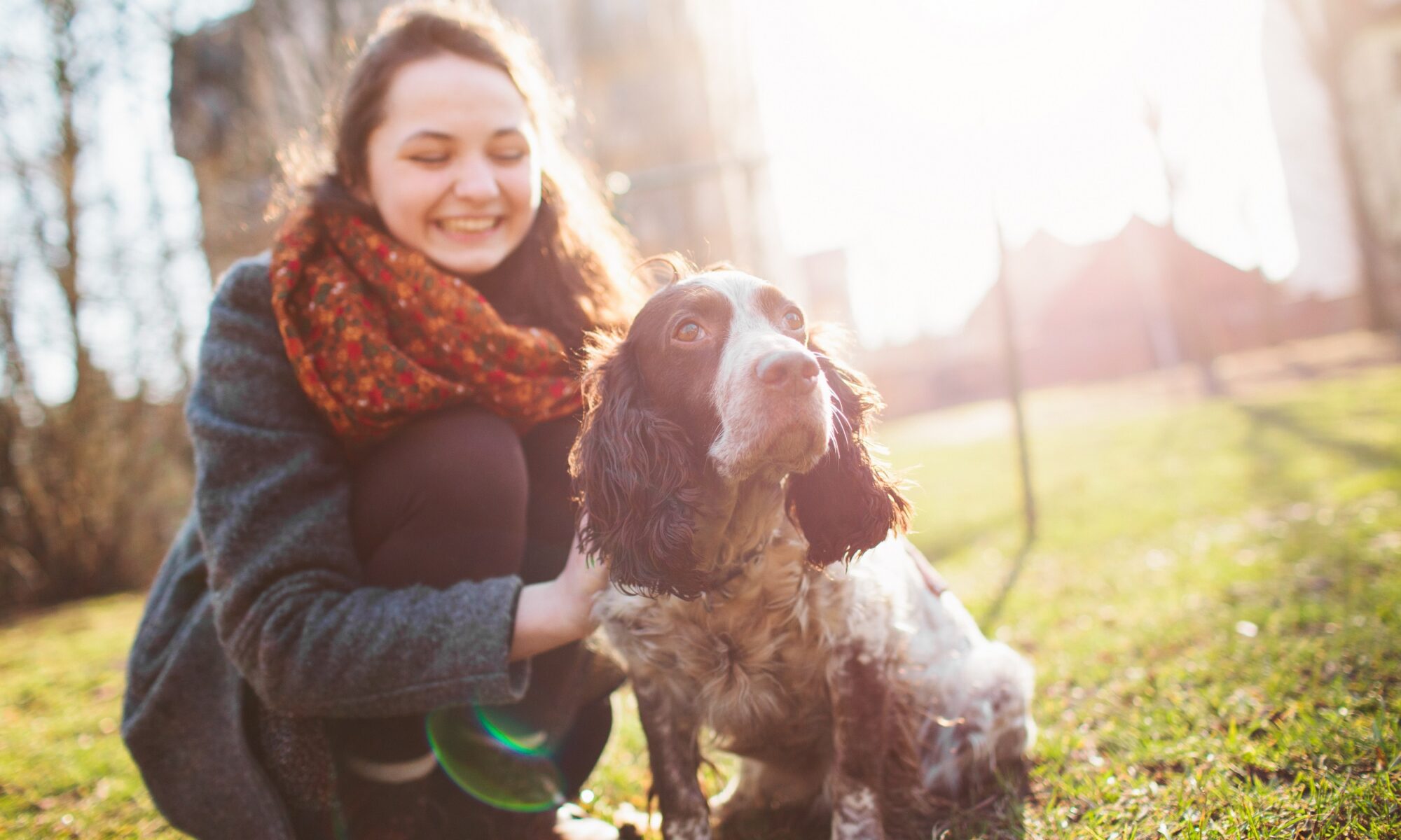 A lady leaning down by her dog